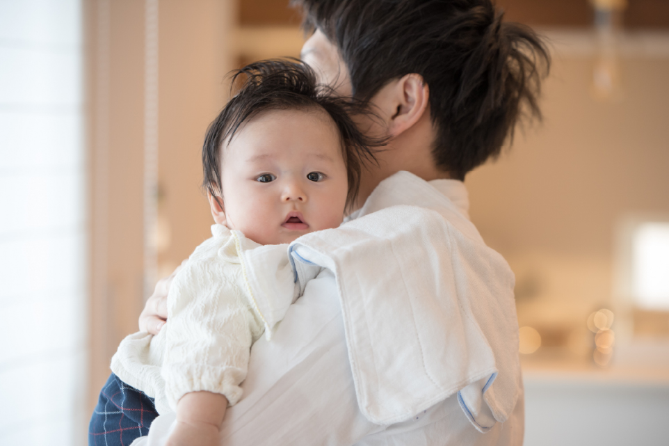 お父さんが赤ちゃんを縦抱きにしてゲップをさせている様子