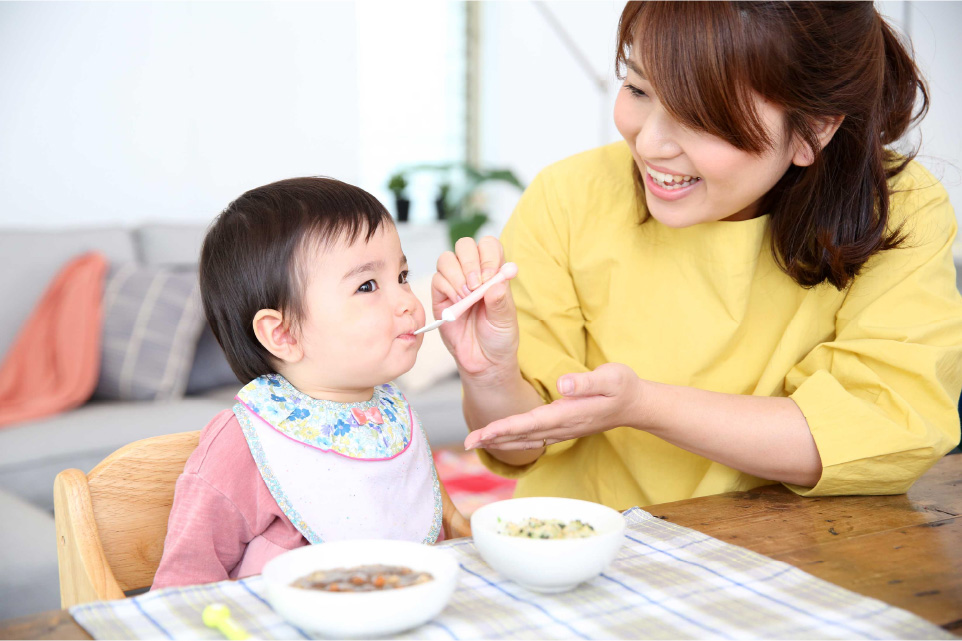 離乳食を赤ちゃんに食べさせるママ